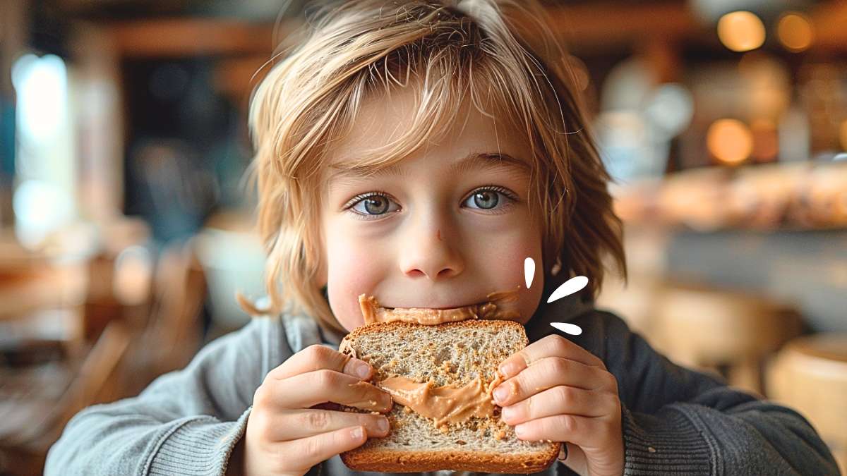 Un bambino mangia un panino con Burro di Arachidi Puro Nextua per una Colazione Proteica adatto anche alla Dieta Chetogenica