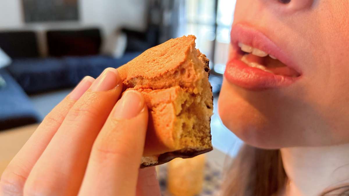 Donna che mangia un plumcake proteico alla vaniglia con base di cioccolato per una colazione proteica o la dieta chetogenica