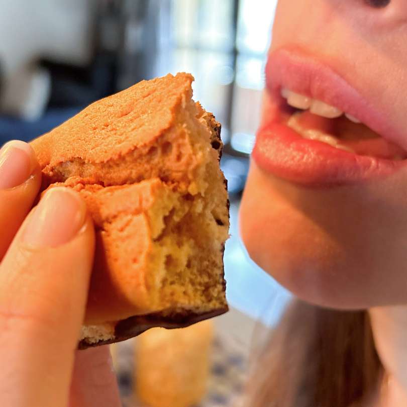 Donna che mangia un plumcake proteico alla vaniglia con base di cioccolato per una colazione proteica o la dieta chetogenica